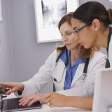 Zwei medizinische Fachangestellte schauen auf einen Laptop