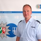 Erster Polizeihauptkommissar Dirk Rufeger steht vor blauer Wand