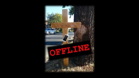 Das Bild zeigt ein Holzkreuz am Straßenrand.