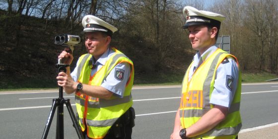 Das Bild zeigt Polizeibeamte bei einer Geschwindigkeitsmessung mit dem Lasergerät.